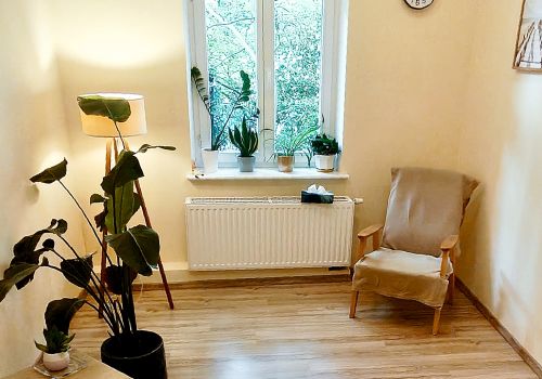 Zdjęcie innego pomieszczenia do terapii indwywidualnej. Na djęciu widać fote, okno. lampę stojącą i duży kwiat w donicy umieszczonej na podłodze.